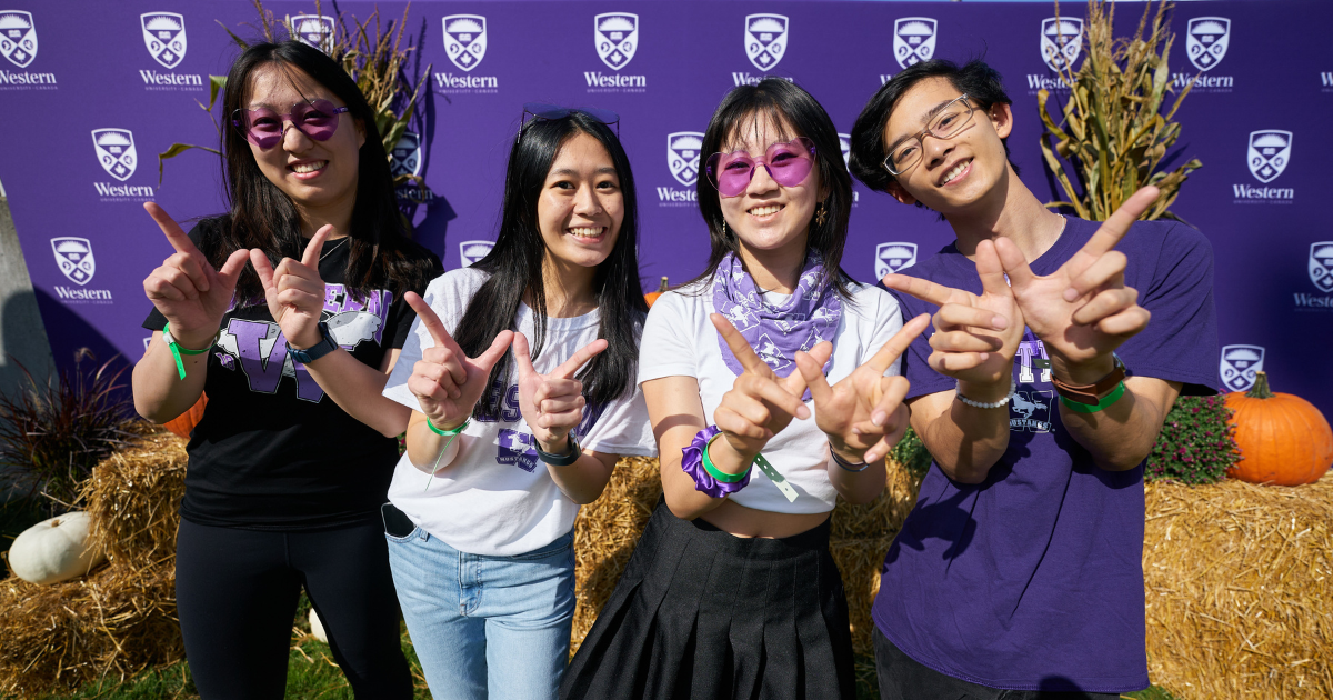 Four Western students posing for a photo with their hands in a W formation for Western.